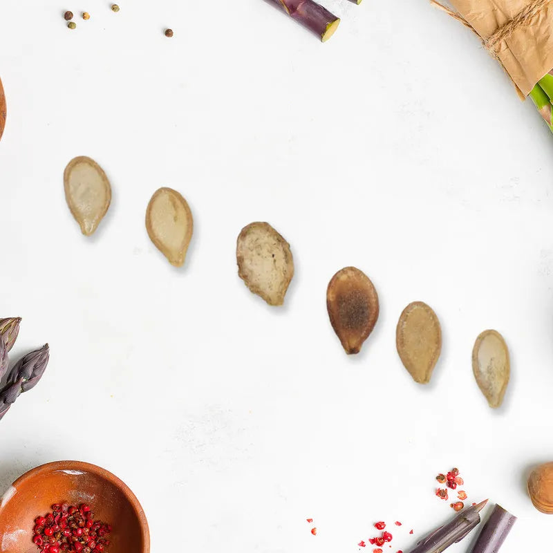 Vegetable seeds scattered around a small bowl with red seeds