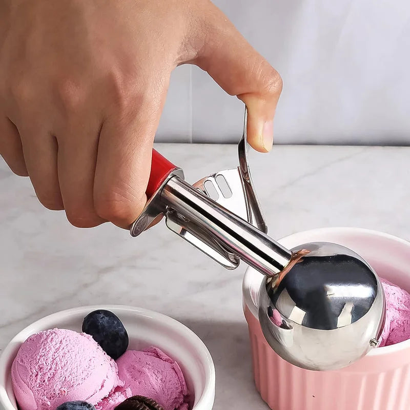 Stainless steel ice cream scooper with black latch, held above bowls