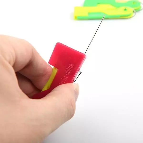 Automatic needle threader tool in red with yellow slot, needle threaded in use