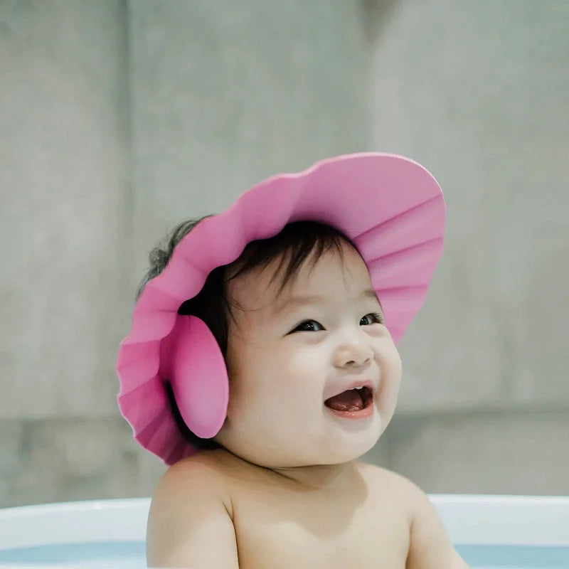 Baby shower protection cap in pink with ruffled ear cover on baby