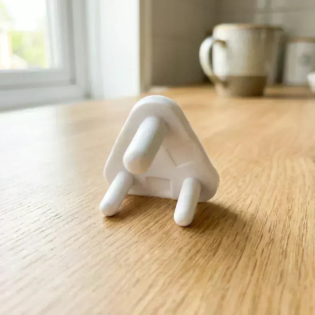 White baby socket cover with three-prong guard, resting on wooden tabletop