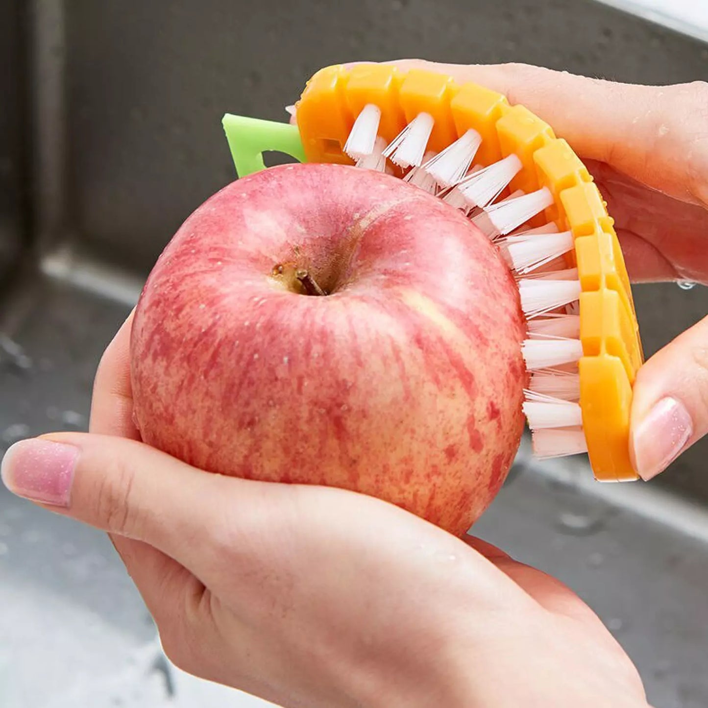 Carrot-shaped vegetable scrub brush with yellow-orange bristles in hand