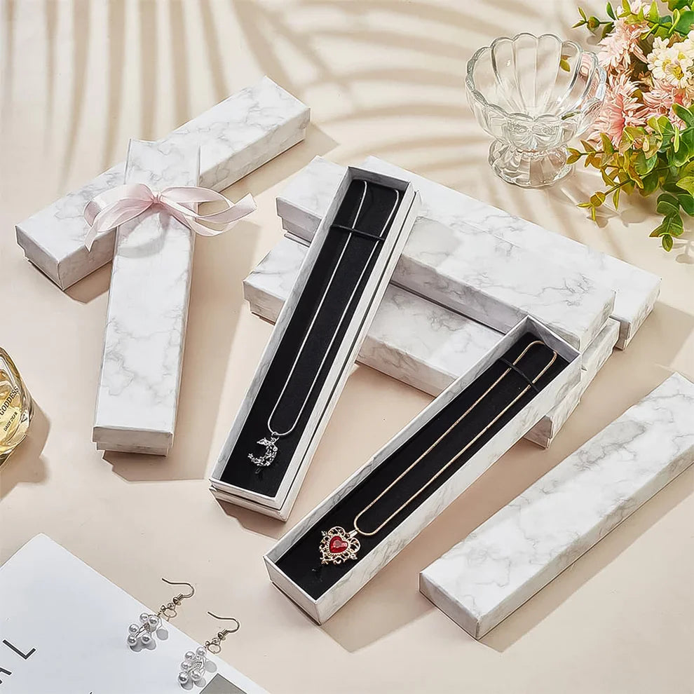 White marble jewelry box with ribbon, open interior with necklace and earrings