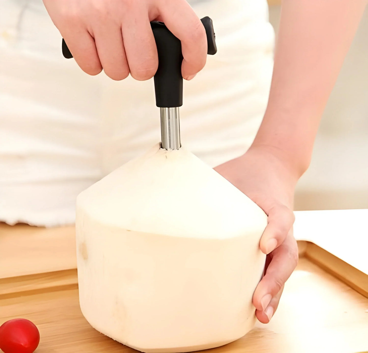 Coconut opener tooldriller with black handle and metal drill bit, held over coconut