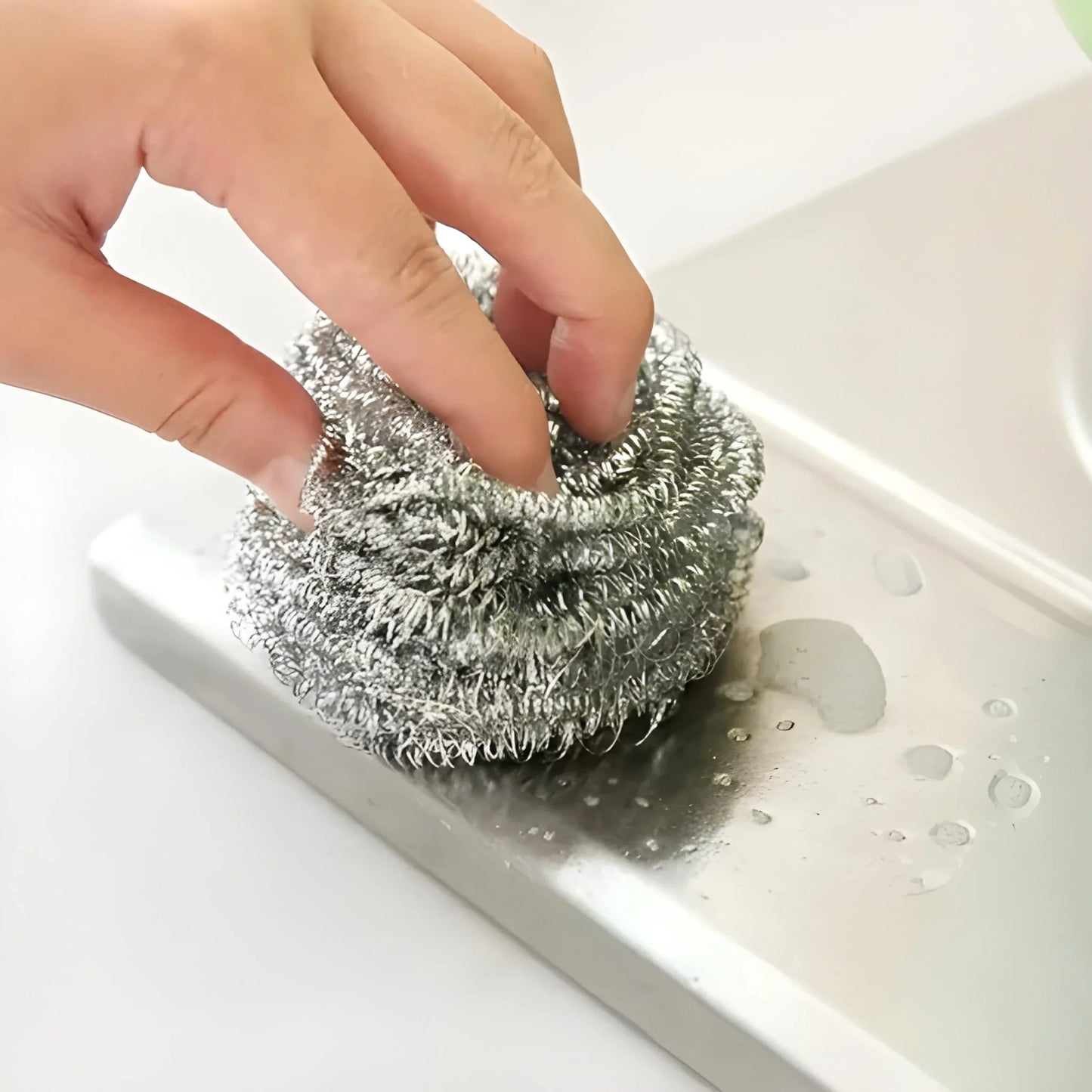 Round stainless steel scrubber with circular metal mesh, handheld for cleaning dishes
