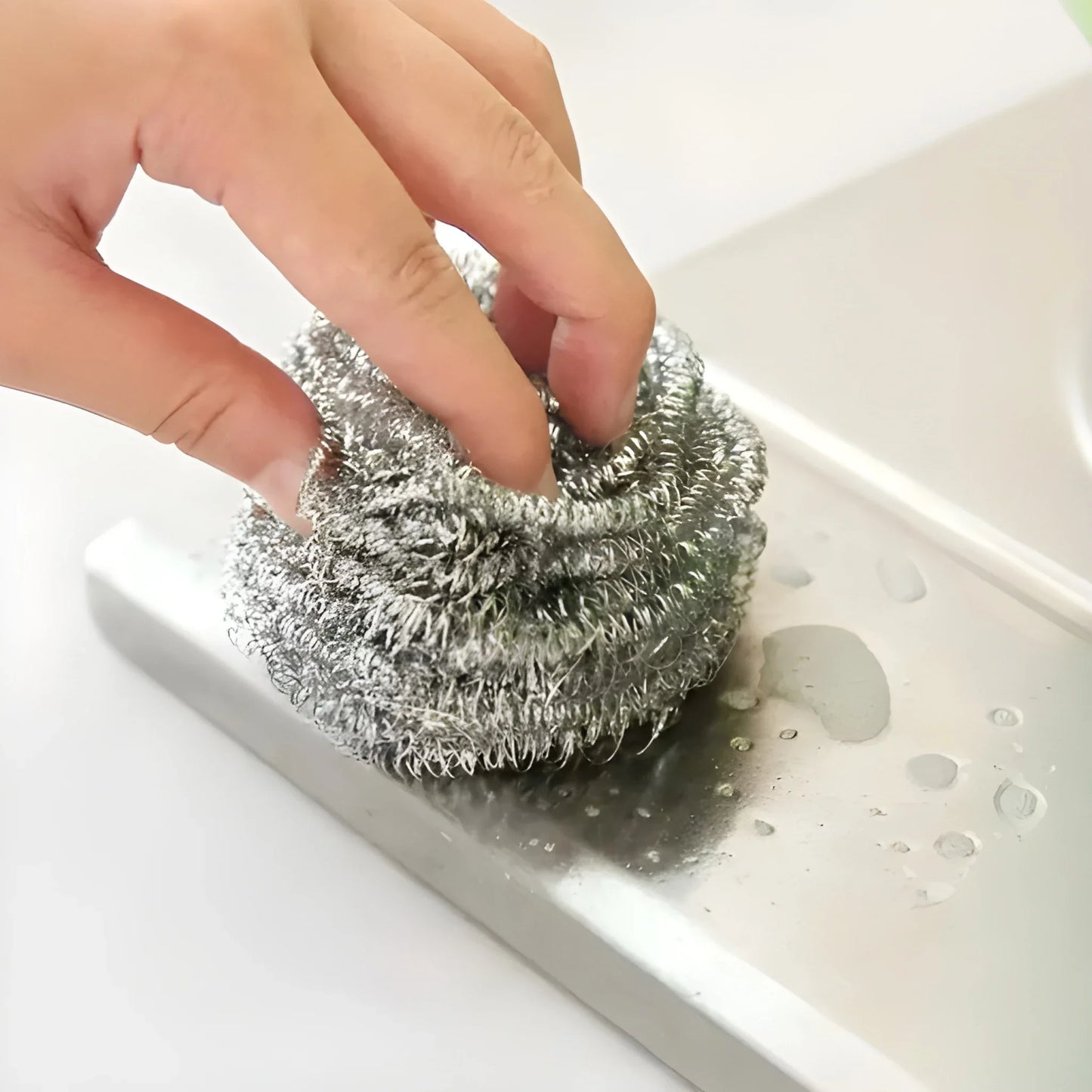 Steel scour ball scrubber, coarse metal mesh ball held over sink