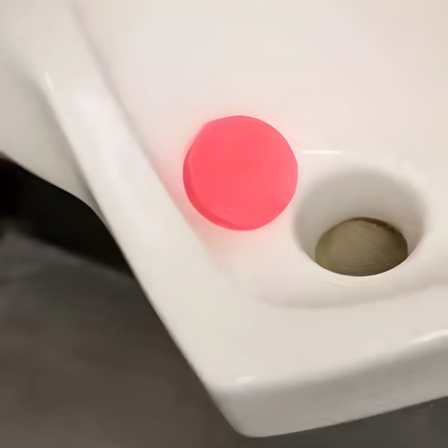 Pink round sanitary urinal cube placed in urinal
