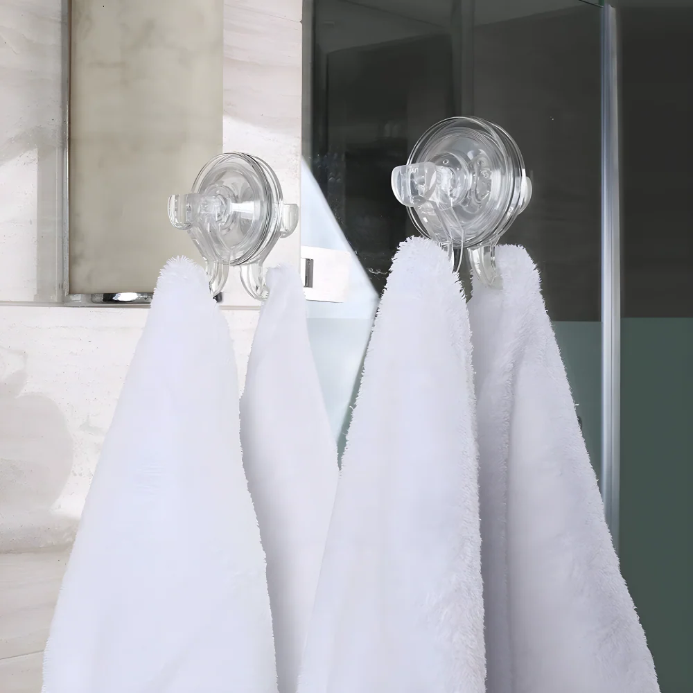 Clear suction cup wall hook with round cap and two-prong hook, holding white towel.