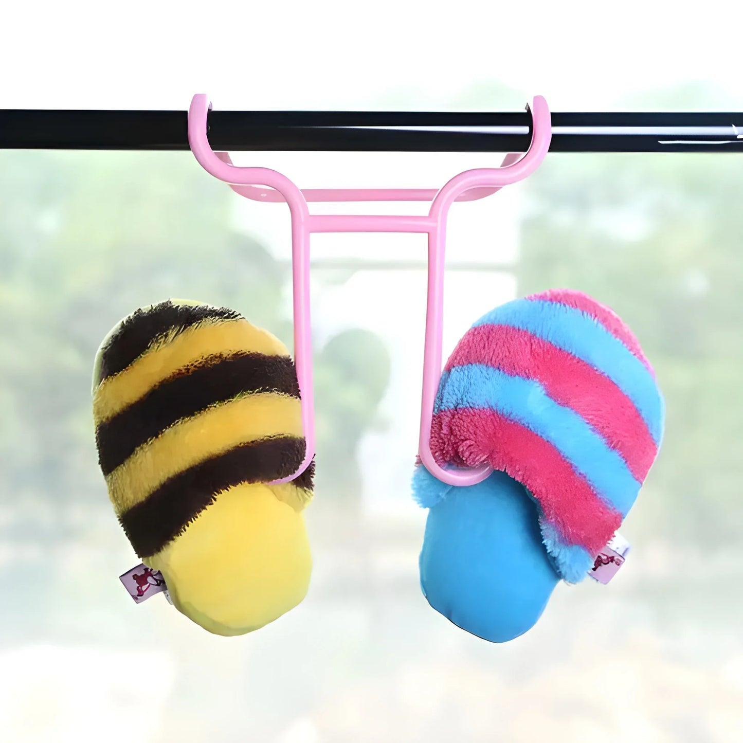 Pink vertical shoe organizer holding striped slippers: yellow and blue on hooks
