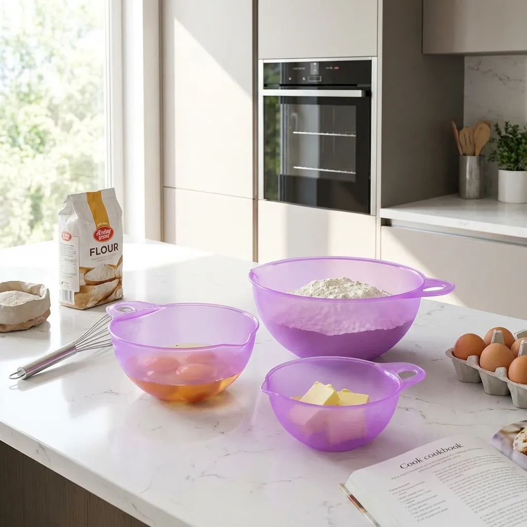 Purple 3-piece prep bowls with handles displayed near flour and eggs on kitchen counter.