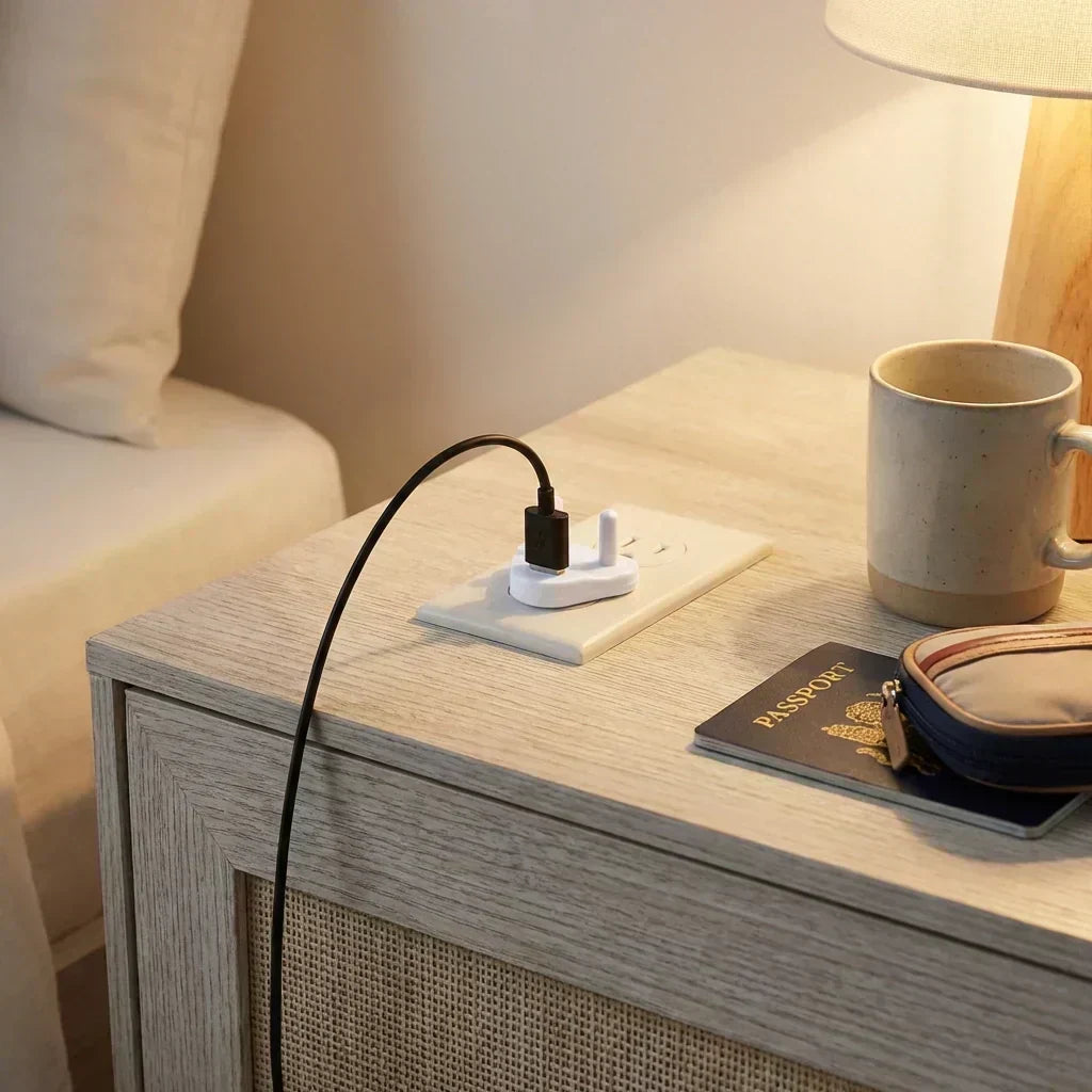 White baby socket cover inserted into a wall outlet on a bedside table