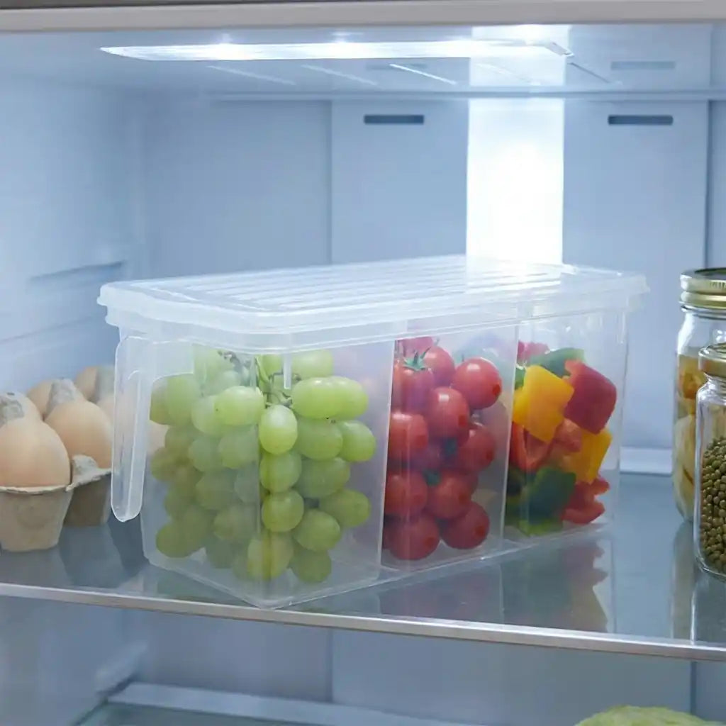 Clear divided refrigerator storage box with colorful produce behind the lid.