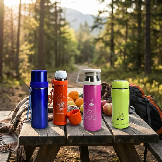 Steel insulated water bottles in blue, orange, pink, green with white caps on picnic table